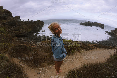 年轻女子站在海边，看着汹涌的大海和浪花