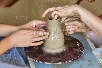 两个人的双手创造出锅，陶工的车轮。教学陶器