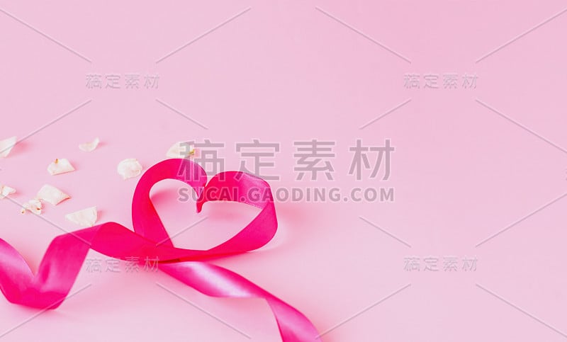 心形节日彩带，粉红色背景，白色玫瑰花瓣。模板模拟贺卡或文本设计。特写镜头