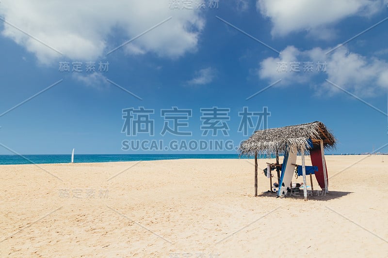 夏天的海滩风景。冲浪板租赁点下的棕榈叶顶篷。海边沙滩上的冲浪板。