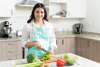 年轻美丽的女人切柿子椒的肖像