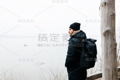 一个年轻人在冬天的早晨站在河边