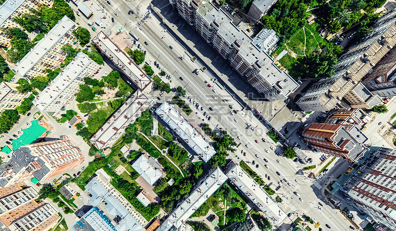 空中城市景观十字路口和道路，房屋，建筑物，公园和停车场。阳光明媚的夏日全景图