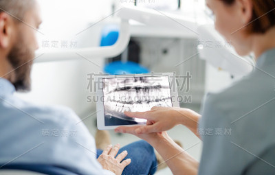 男人和牙医的后视图在牙科手术，每年检查。