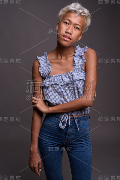 工作室拍摄的美丽叛逆的年轻女子短发与灰色的背景