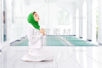 亚洲穆斯林妇女戴面纱坐在祈祷位置，同时举起双手祈祷