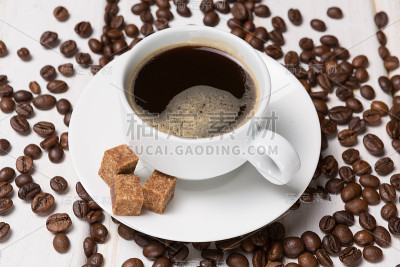 白木桌上的瓷杯里泡着黑咖啡，咖啡豆和红糖撒在一起