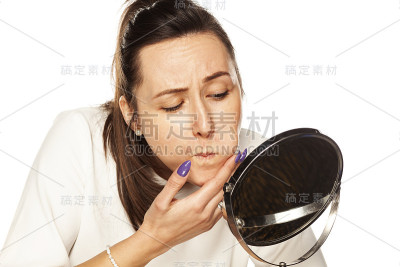 一个女人对着镜子看自己的脸