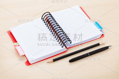 办公室桌子上有空白的记事本，钢笔和铅笔