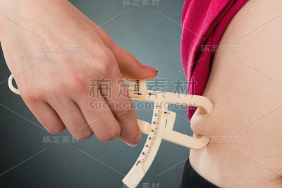 女性的手测量肥胖的肚子