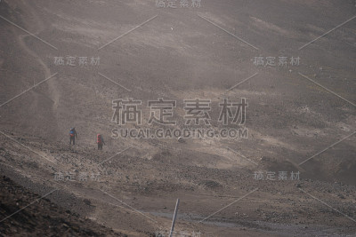 两个徒步旅行者在火山灰风暴期间的火山景观在Fimmvorduhals徒步小径。冰岛