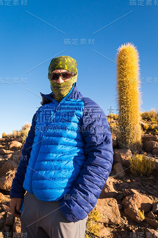 旅游背包客站在山上巨大的仙人掌，乌尤尼盐湖，玻利维亚。