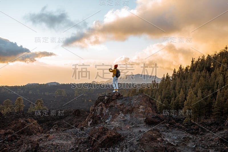 日落时分在火山上旅行的女人