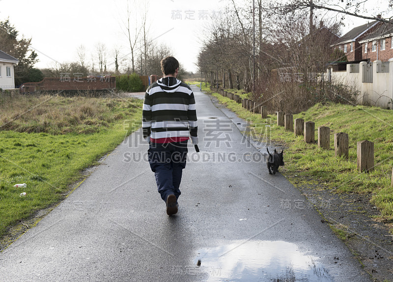 一个三十多岁的男人在遛他的宠物苏格兰梗