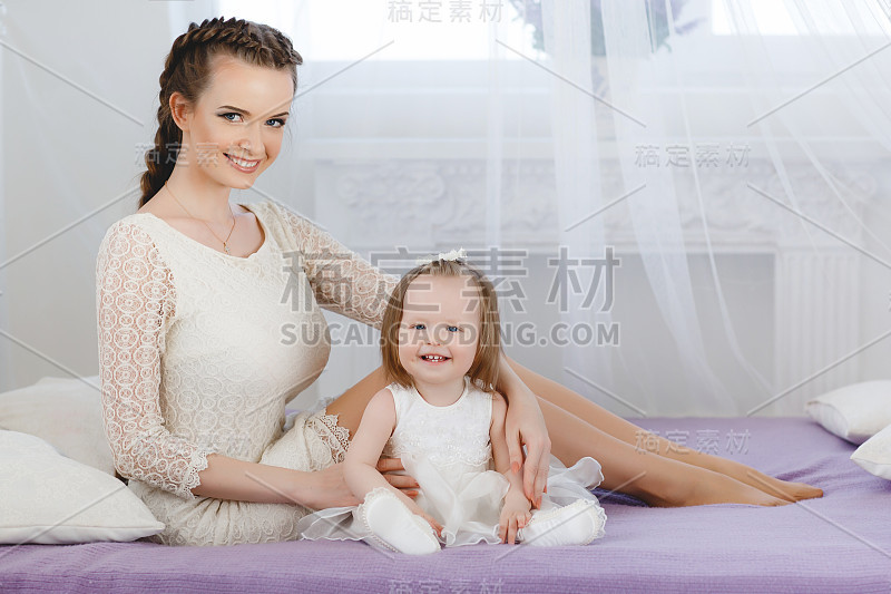 一个快乐的妈妈和她的小女儿在卧室的床上玩。