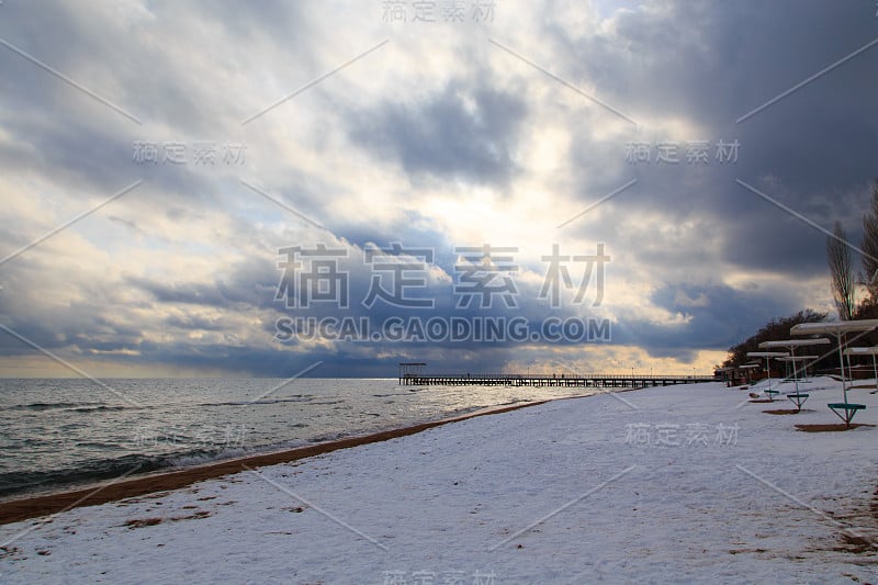 冬天的海滩。蓝色清澈的海水，沙滩上的雪。地平线和山脉。吉尔吉斯斯坦、吉湖