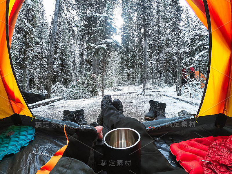 在国家公园的松林里，游客手拿着杯子在一个有雪的帐篷里露营