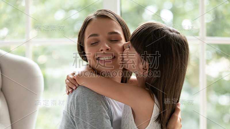 可爱的小女孩拥抱亲吻年轻的母亲
