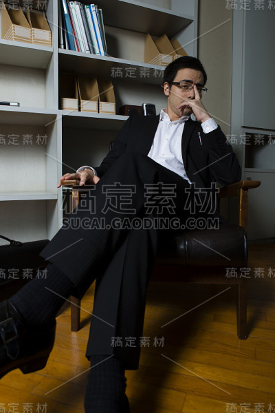 一个商人坐在书架前的椅子上