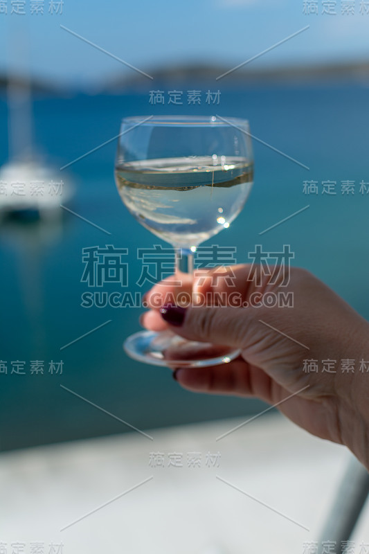 女人手里拿着一杯酒和蓝色的海景