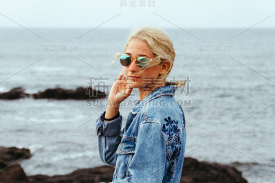 年轻时尚的女人在海岸边摆姿势，以海浪为背景