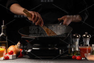 厨师烹饪。用平底锅煎菜。餐厅经营，以黑色为背景，横放照片。食材、咖啡或餐饮业务。