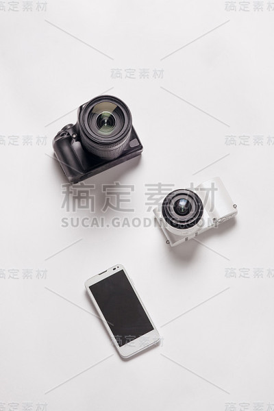 单反相机和智能手机放在白色背景上。摄影师