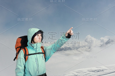 登山家指着山顶，站在一个冬季的山景