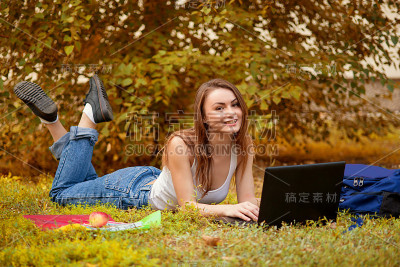 学生女孩在草地上与电脑