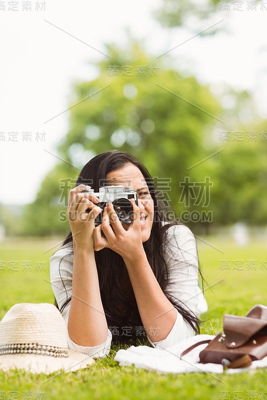 微笑的黑发女子躺在草地上拍照