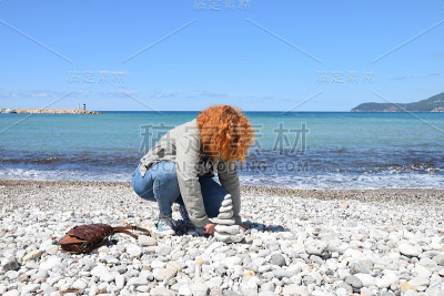 女人在海滩上建造石塔
