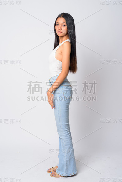全身拍摄侧面的年轻美丽的亚洲女人看相机