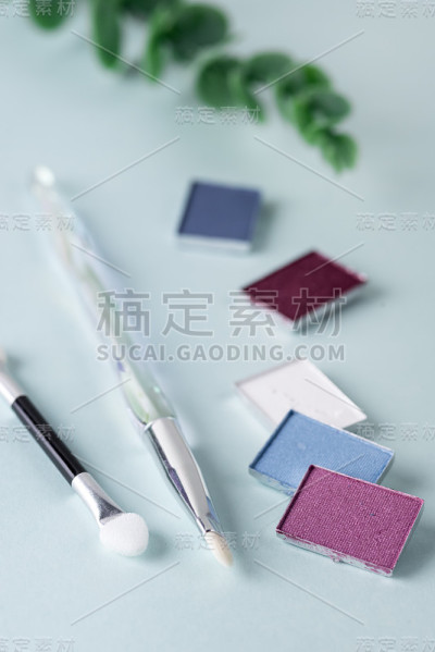 各种眼影和笔刷在蓝色背景上的概念垂直化妆