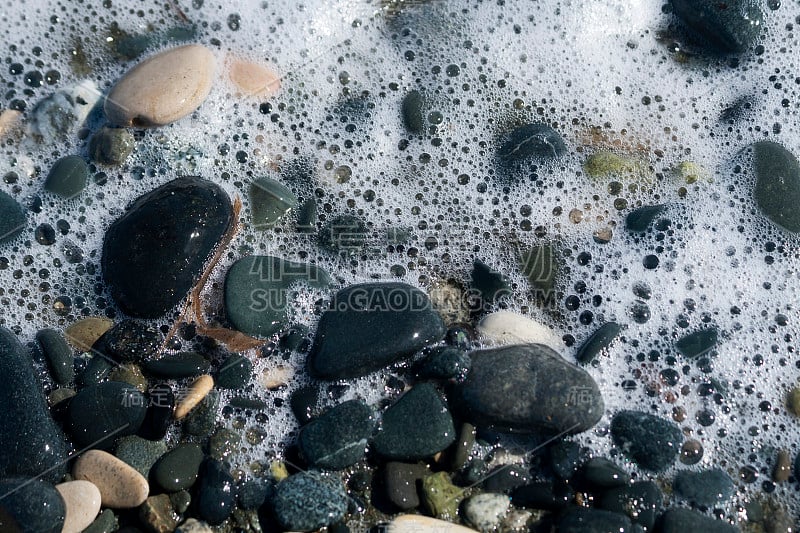 海滩卵石在泡沫状的海水中