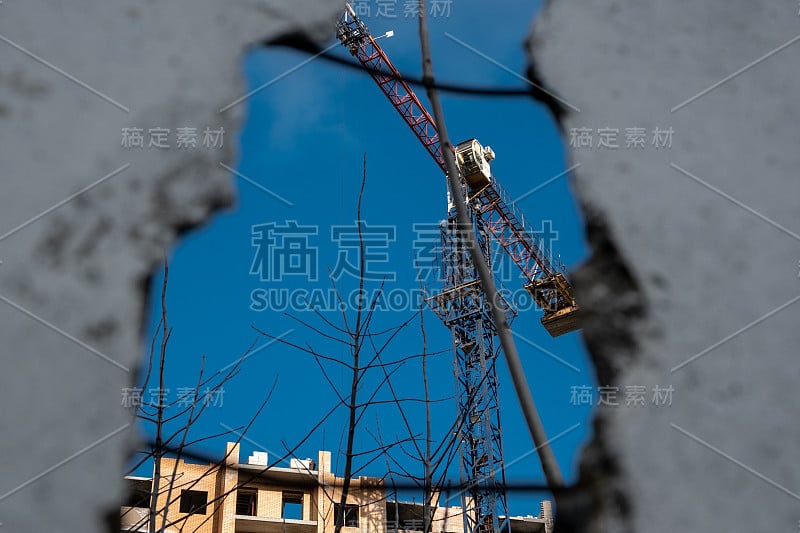 施工现场起重机。吊车和正在施工的楼房从蓝天老旧受损的房子