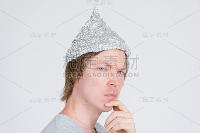 特写镜头的年轻人与锡纸帽思考和看相机