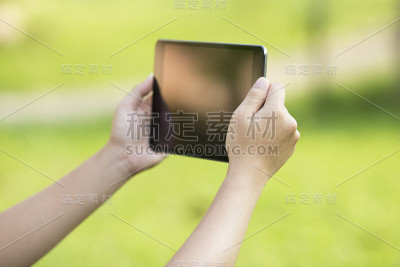 女性在公园使用平板电脑