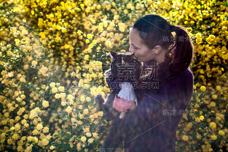 女人在外面亲吻猫咪，背景是微笑的花朵