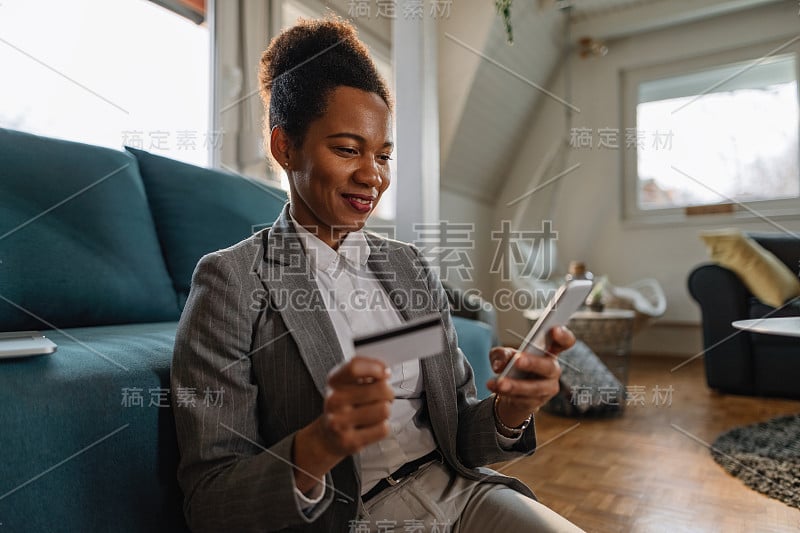 快乐的非裔美国女商人用信用卡和智能手机进行手机银行业务。