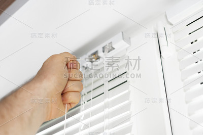 男子在窗户上安装活动百叶窗。