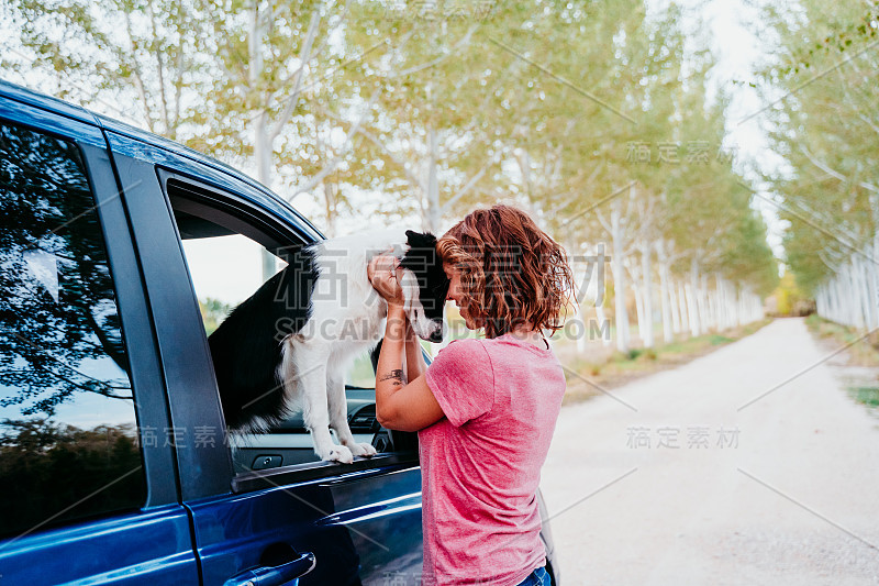 一个女人在一辆面包车里抱着她的边境牧羊犬。旅游的概念