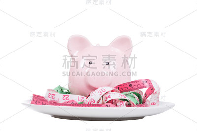 盘子上放着带卷尺的粉色储蓄罐