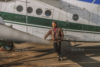 有魅力的成年男子站在飞机附近