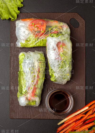 木板上的春卷。靠近酱油，青椒和青菜