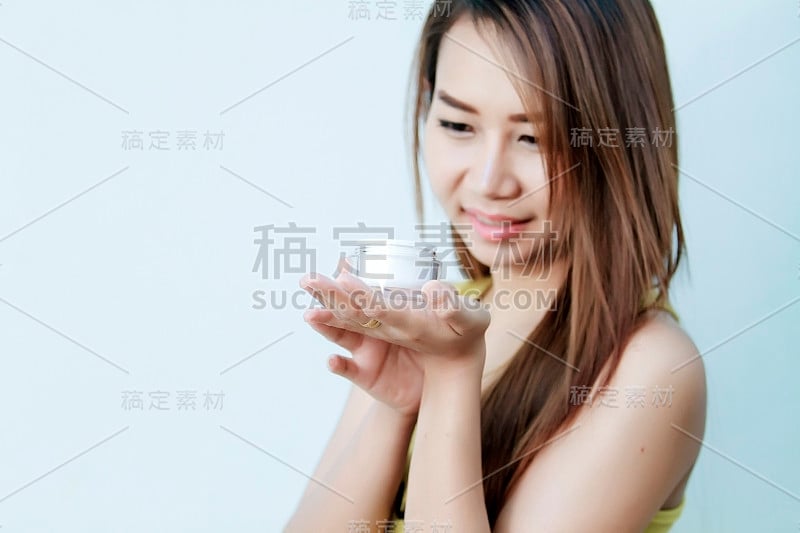 美丽的亚洲女性使用皮肤护理产品，保湿或