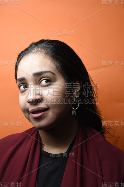 工作室拍摄的年轻美丽的埃及少女与黑色的头发与橙色的背景