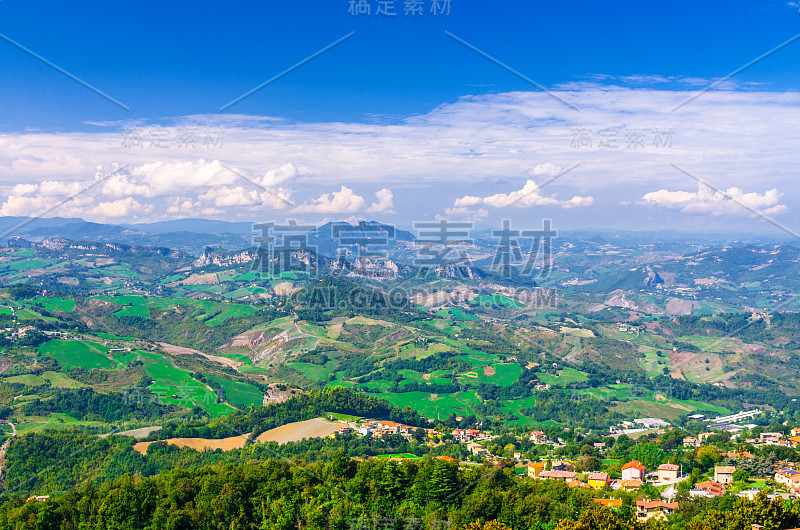 空中顶部全景景观与山谷，绿色的山丘，田野和村庄的共和国圣马力诺郊区与蓝天白云的背景。从圣马力诺要塞观