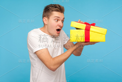 一名身穿白色t恤的男子用好奇和惊讶的表情看着礼盒里面