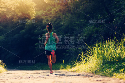 年轻的健身女运动员在森林小径上跑步