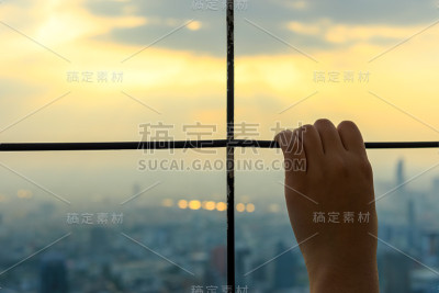 年轻的手放在钢笼上